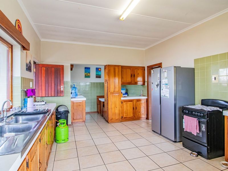A functional kitchen featuring wooden cabinetry, tiled splashbacks, and tiled flooring, offering a traditional layout with ample storage and workspace.