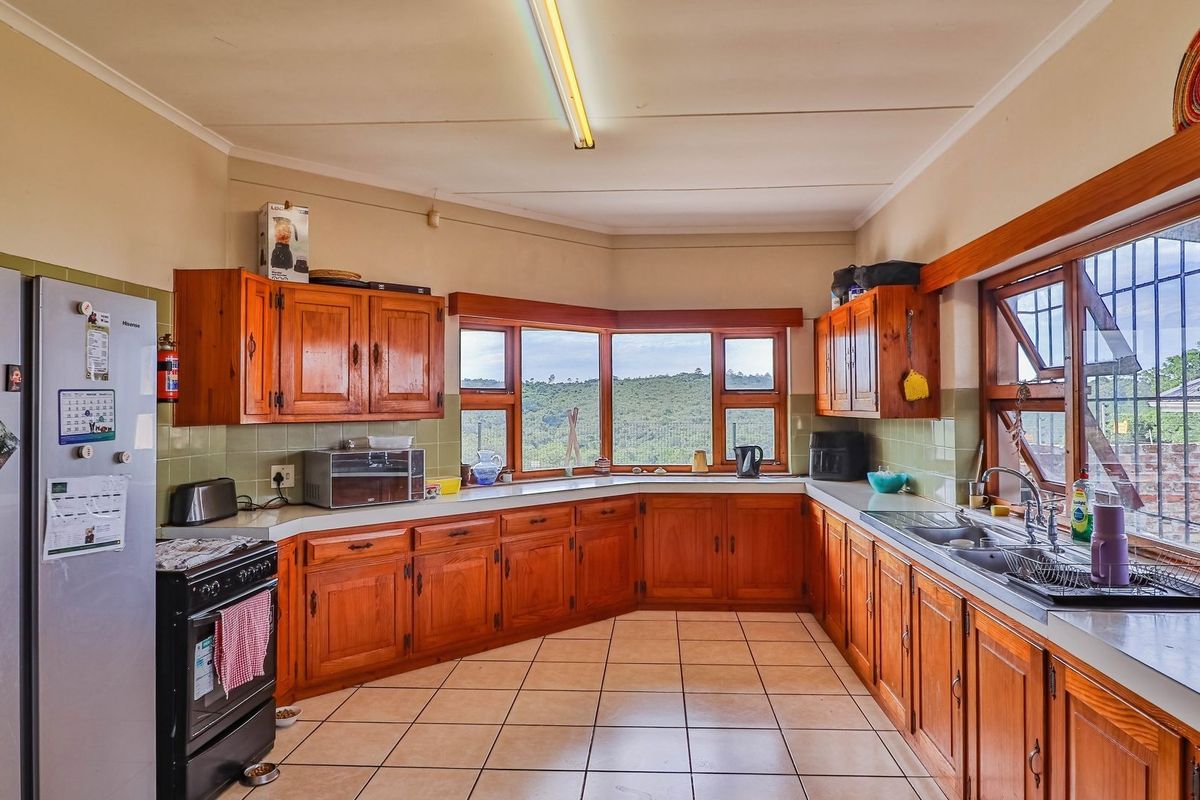 A spacious kitchen featuring traditional wooden cabinetry, tiled flooring, and a large bay window offering scenic views, providing a functional layout with ample storage.