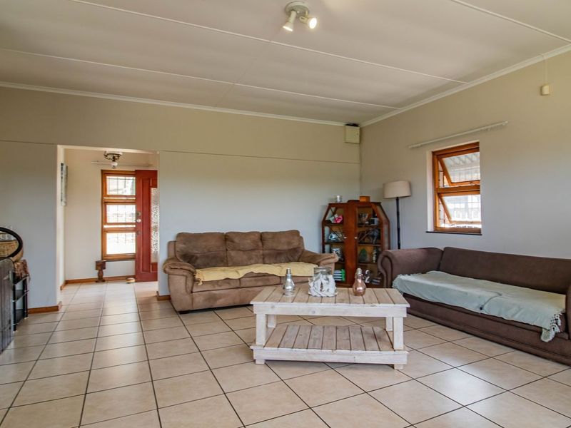 Spacious living room featuring neutral tiled flooring and timber window frames, offering a functional and well-lit area for relaxation.