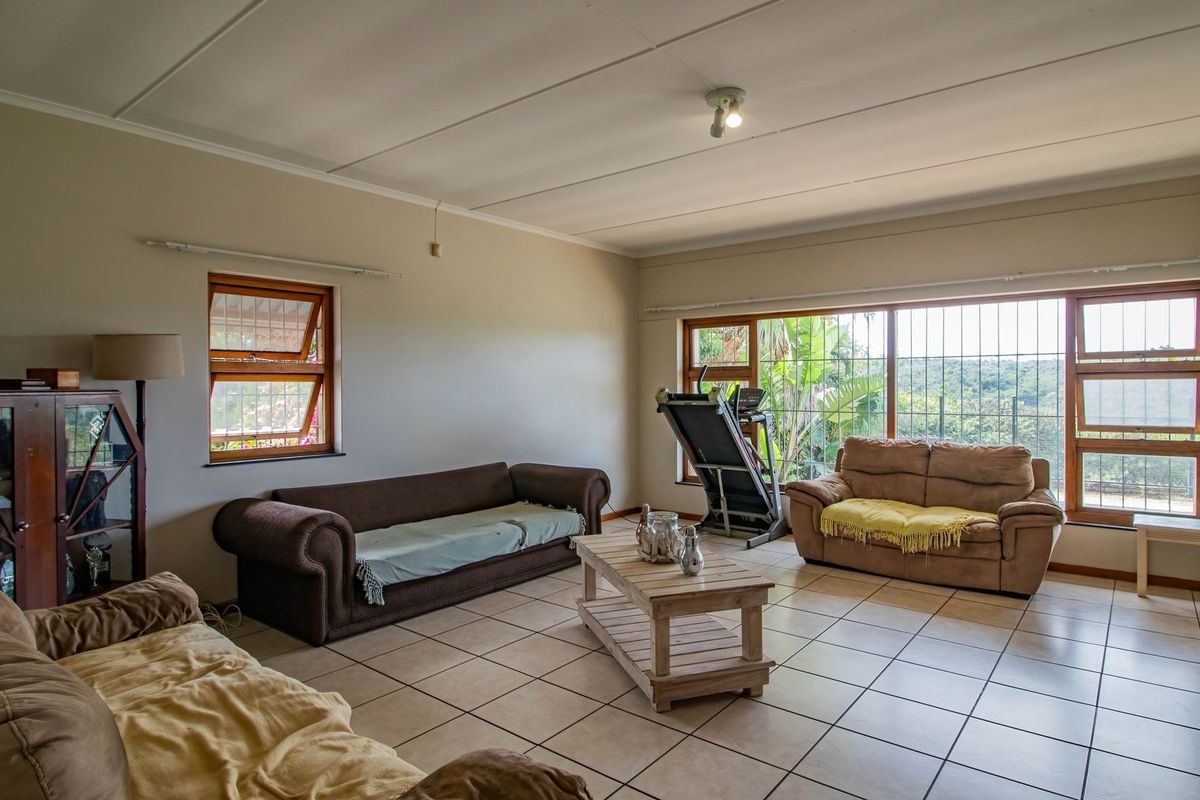 Spacious living room featuring neutral tiled flooring, large windows with security bars, and ample natural light, offering a comfortable and functional living space.