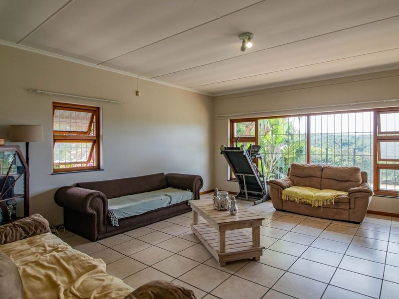 Spacious living room featuring neutral tiled flooring, large windows with security bars, and ample natural light, offering a comfortable and functional living space.