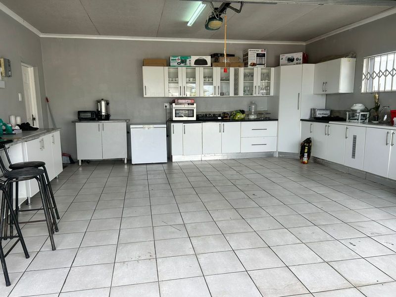Spacious garage featuring extensive built-in cabinetry, tiled flooring, and a security-barred window, offering versatile storage or utility space.