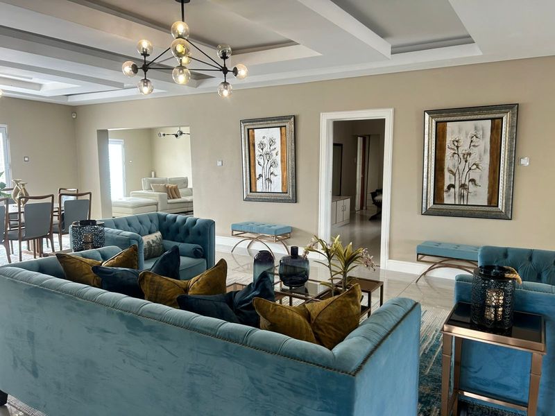 Spacious living room featuring a coffered ceiling with recessed lighting and polished tile flooring, providing an elegant and well-maintained open-plan living space.