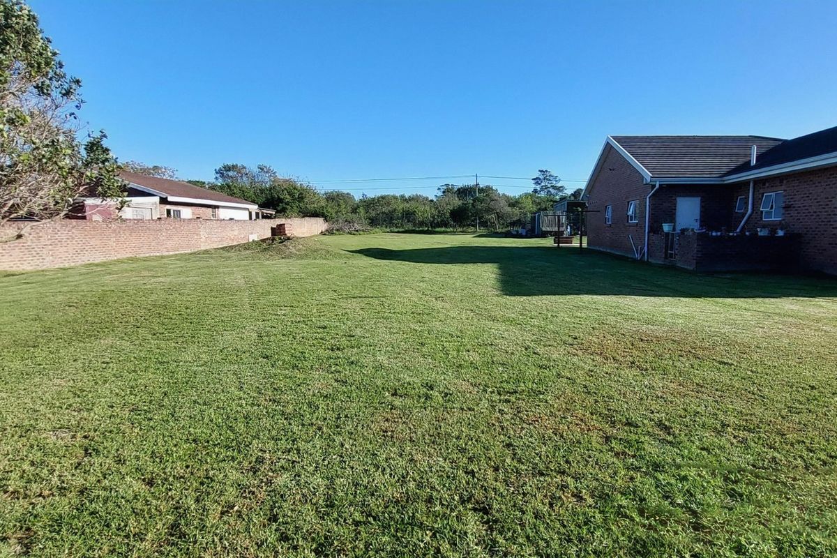 A spacious rear garden area featuring a well-maintained lawn, enclosed by a brick boundary wall, adjacent to the rear elevation of the residential dwelling.