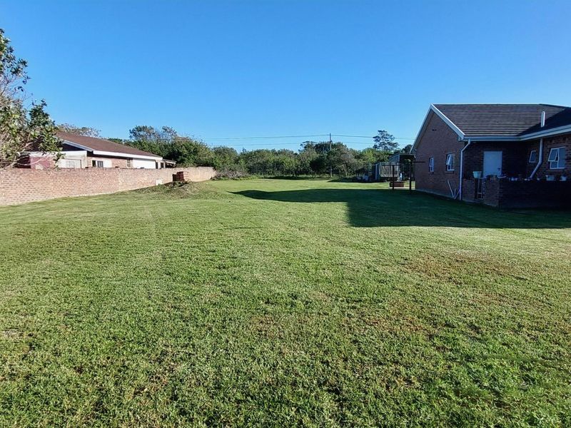 A spacious rear garden area featuring a well-maintained lawn, enclosed by a brick boundary wall, adjacent to the rear elevation of the residential dwelling.