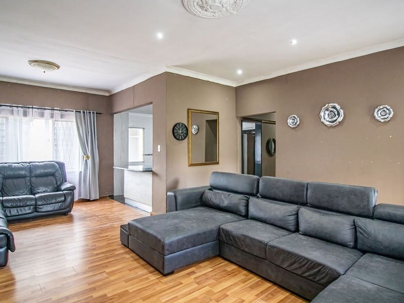 Open-plan living area featuring laminate flooring, recessed downlighting, and a breakfast bar connecting to the kitchen space.
