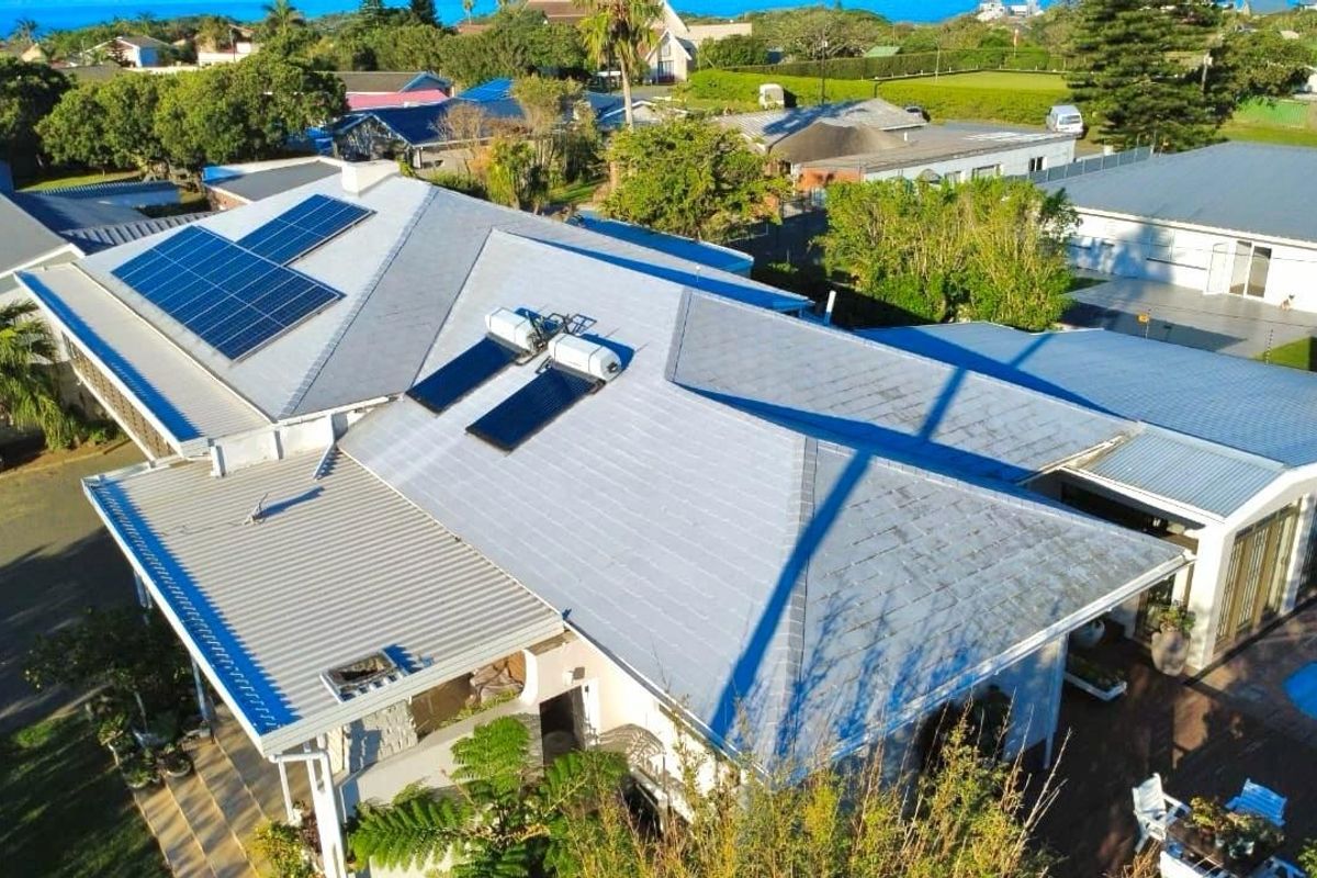 Aerial view of the property showcasing the roof structure, equipped with solar panels and a solar water heating system.