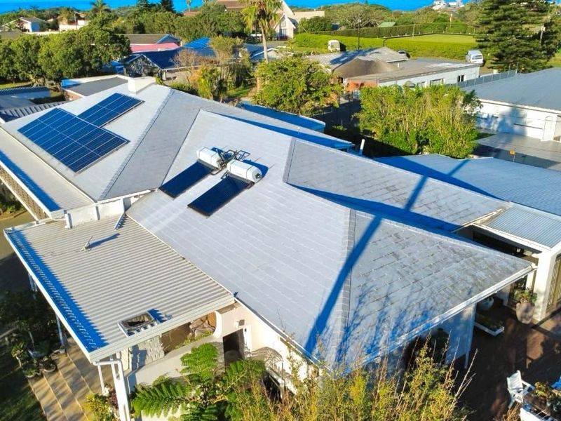 Aerial view of the property showcasing the roof structure, equipped with solar panels and a solar water heating system.
