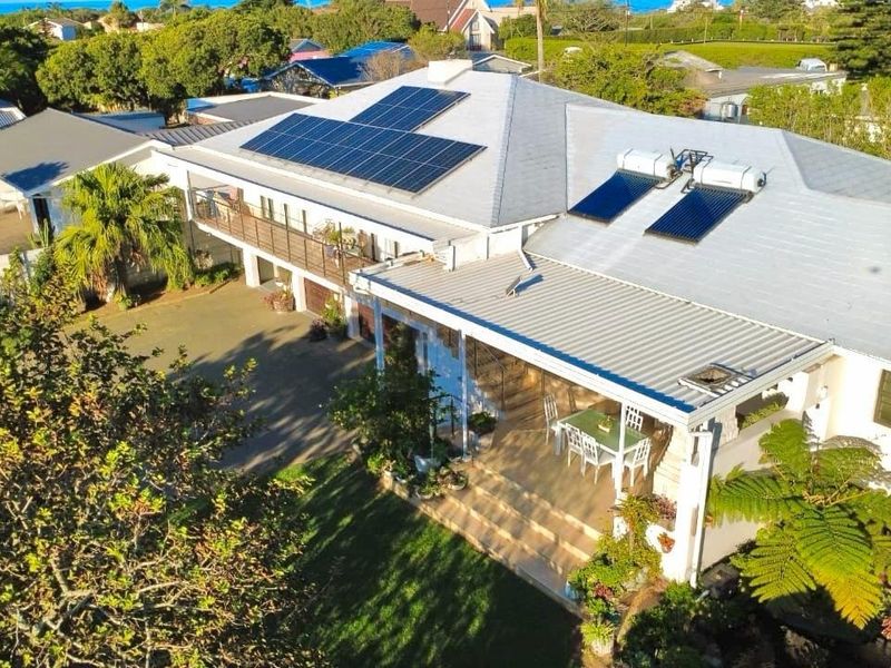Aerial view of the property featuring a metal roof with installed solar panels and solar water heating, a covered patio, and a balcony.