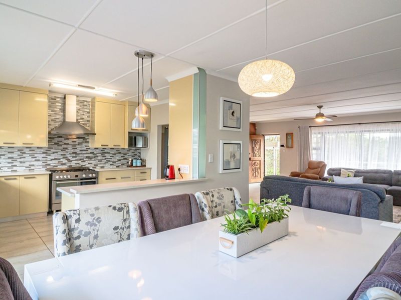 Spacious open-plan living area featuring a modern kitchen with built-in cabinetry, gas stove, and tiled finishes, flowing into a comfortable dining and lounge space.