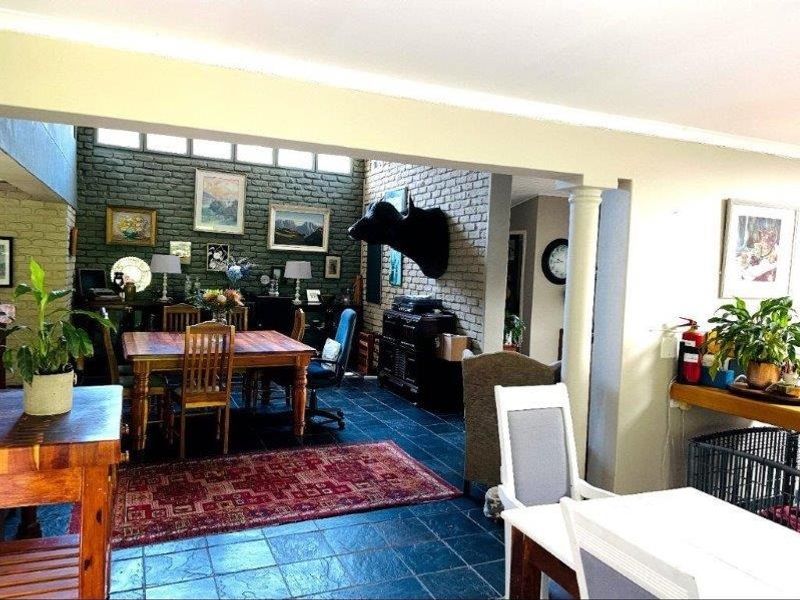Spacious open-plan living and dining area featuring exposed brick walls, clerestory windows for natural light, and durable stone tile flooring.