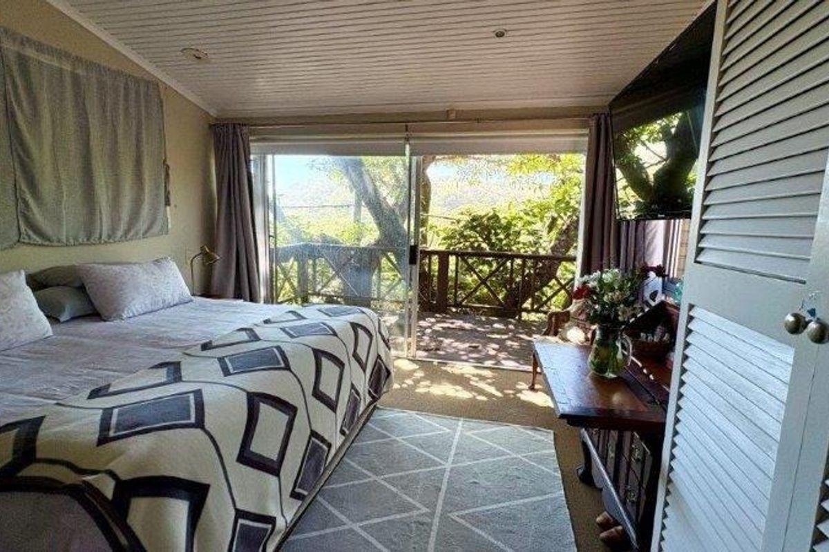 Bedroom featuring a timber ceiling, built-in wardrobe, and sliding glass doors that open onto a private balcony with scenic views.
