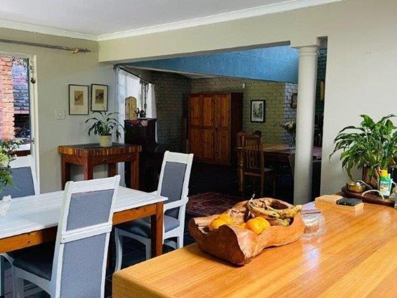 Open plan living and dining area featuring tiled floors, exposed brickwork, and a structural column, with direct access to an outdoor patio space.