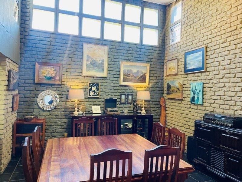 A dining room featuring high ceilings with clerestory windows, exposed brick walls, and tiled flooring, creating a characterful and well-lit space.