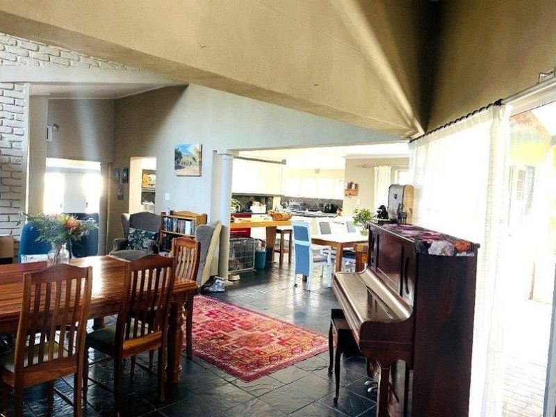Spacious open-plan living and dining area featuring vaulted ceilings, slate flooring, and a prominent brick fireplace, flowing into the kitchen space.