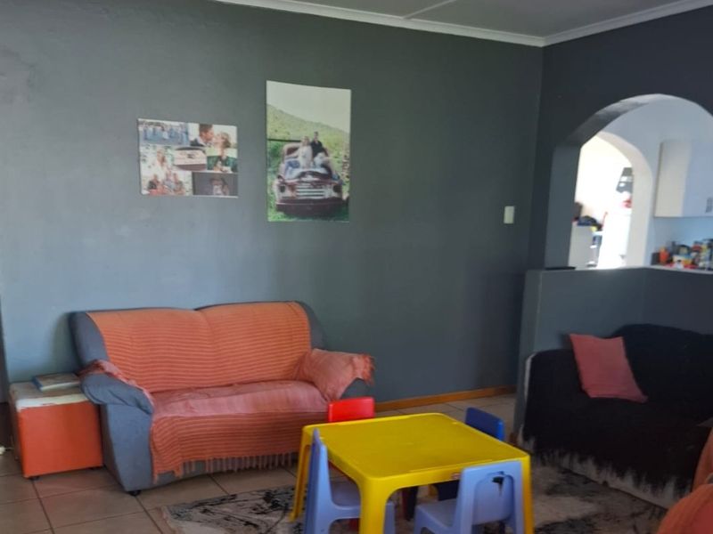 A living room area featuring tiled flooring and an arched opening leading to an adjacent space, finished with dark grey wall paint.