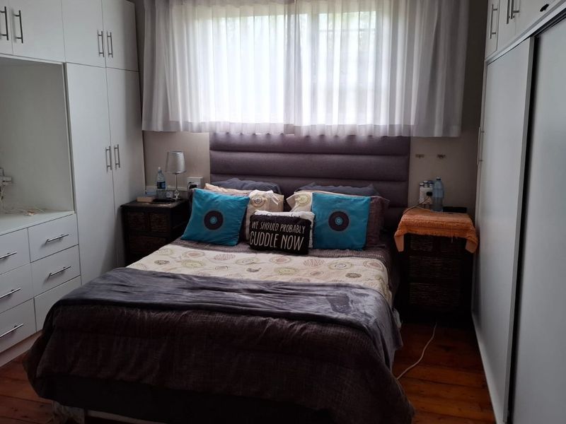 A well-maintained bedroom featuring extensive built-in white cabinetry, a neutral upholstered headboard, and warm hardwood flooring.