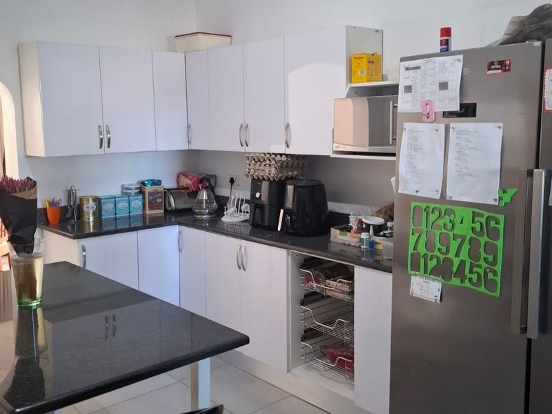 A functional kitchen featuring white cabinetry, dark granite countertops, and integrated storage solutions, providing a practical workspace for daily meal preparation.
