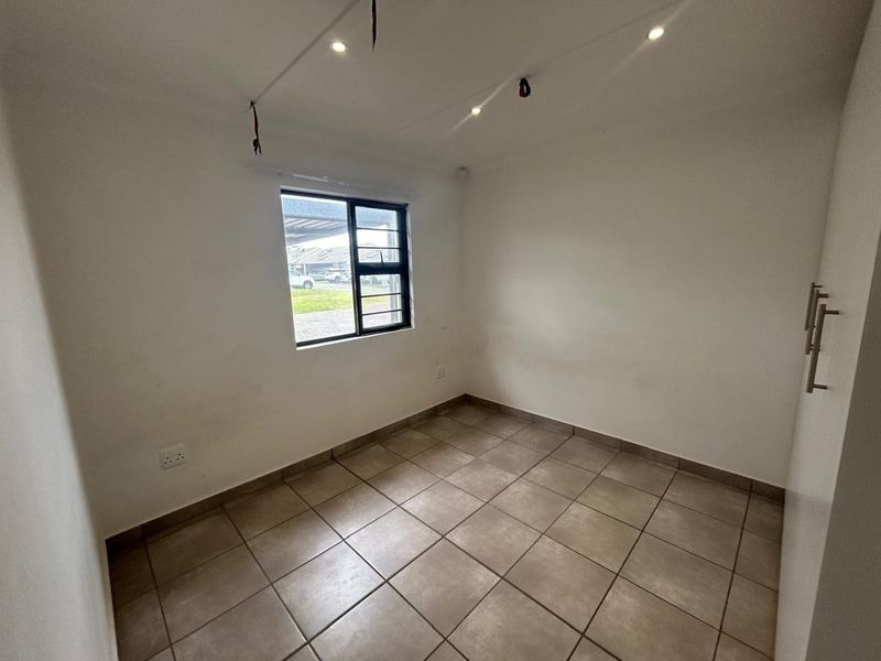 An empty bedroom featuring tiled flooring, a built-in cupboard, and a window with security bars, ready for personalization.