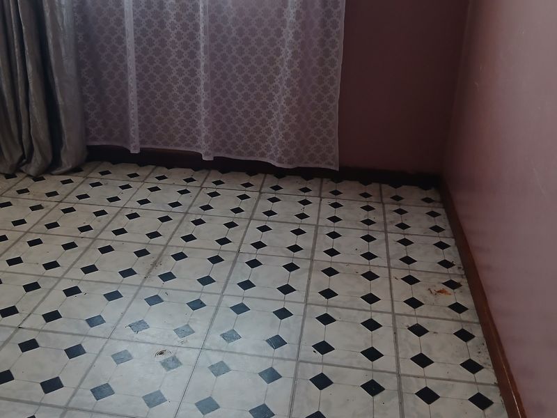 An empty bedroom featuring classic black and white patterned floor tiles and simple wall finishes, ready for renovation or restyling.