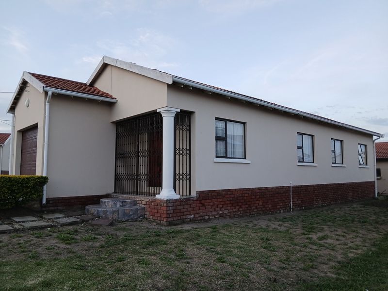 A well-maintained single-story house featuring a tiled roof, brick base detailing, and a secure entrance with a decorative column.