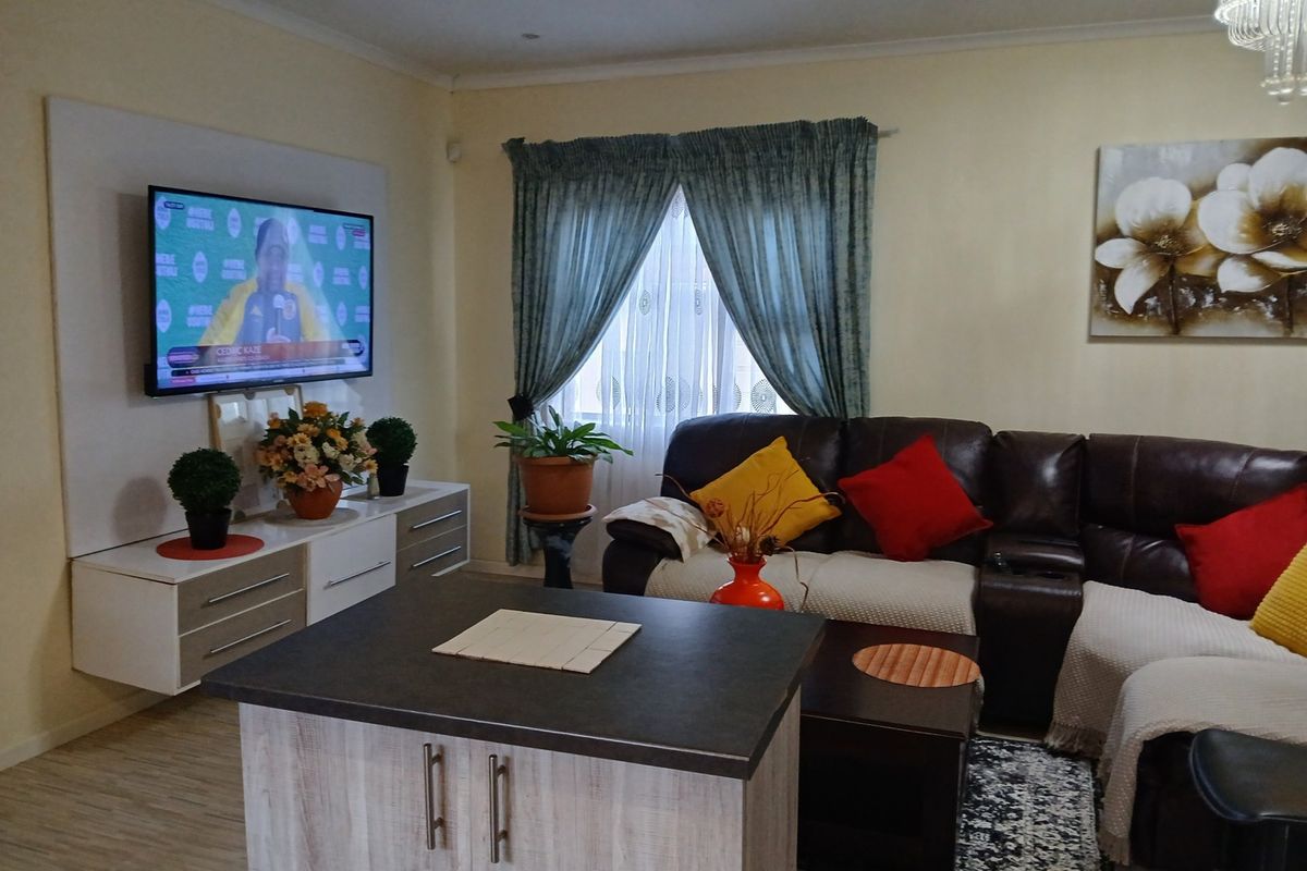 A comfortable living room featuring laminate flooring, recessed ceiling lighting, and a custom built-in media wall unit.