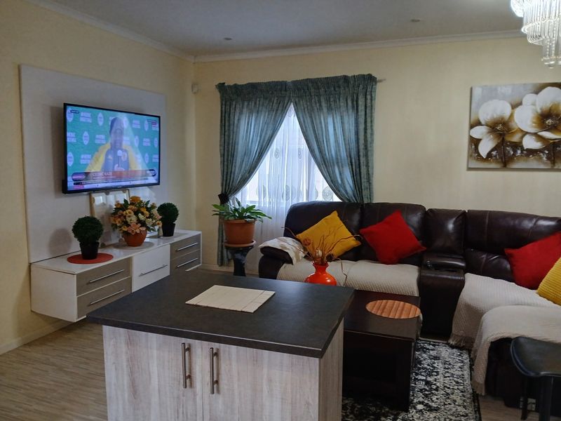 A comfortable living room featuring laminate flooring, recessed ceiling lighting, and a custom built-in media wall unit.