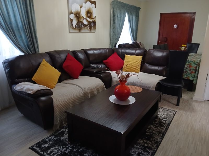 A comfortable living room featuring light-toned laminate flooring and a solid timber entrance door, providing a functional and neutral base for the home.