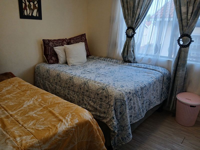 A functional bedroom featuring laminate flooring and window treatments, providing a comfortable space with natural light.