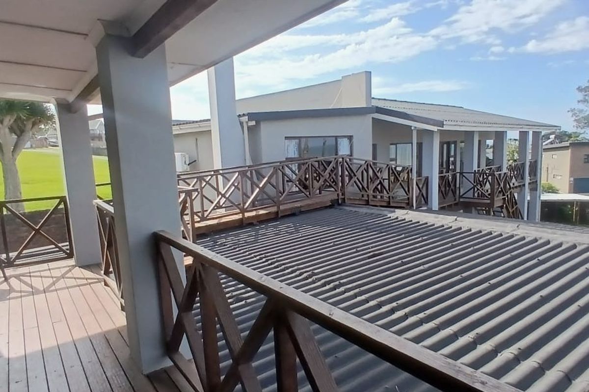 Spacious elevated wooden balcony featuring a covered area and wooden balustrades, offering an outdoor space with views of the surrounding property.