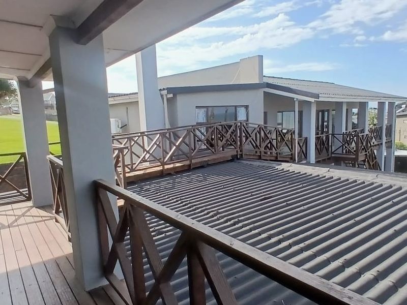 Spacious elevated wooden balcony featuring a covered area and wooden balustrades, offering an outdoor space with views of the surrounding property.