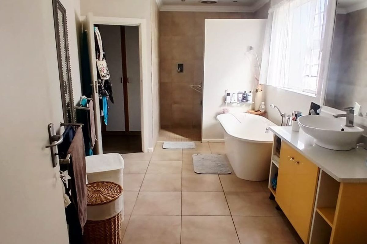 Spacious bathroom featuring a freestanding bathtub, a walk-in shower with tiled walls, and a vanity unit with a modern vessel sink.