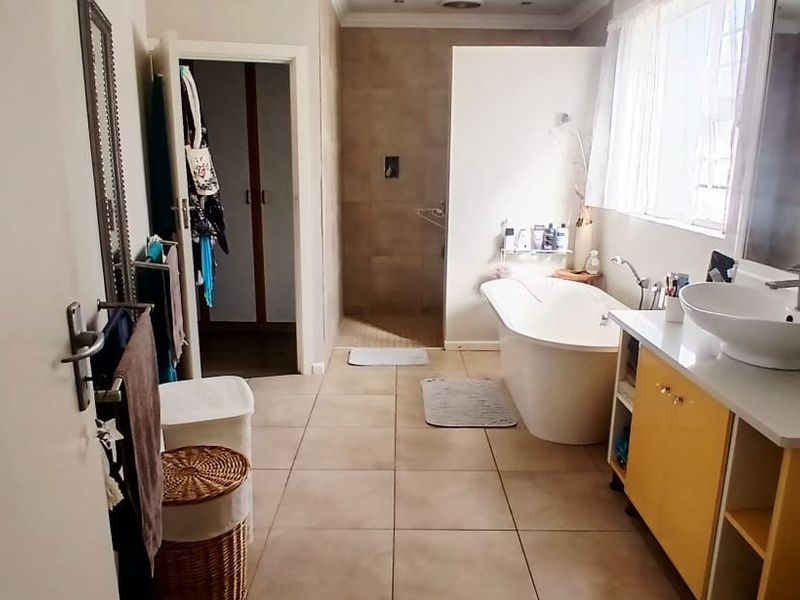Spacious bathroom featuring a freestanding bathtub, a walk-in shower with tiled walls, and a vanity unit with a modern vessel sink.