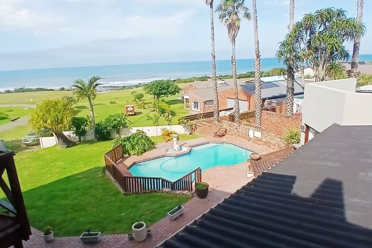 Elevated view overlooking a private swimming pool, landscaped garden, and coastal scenery with ocean views.