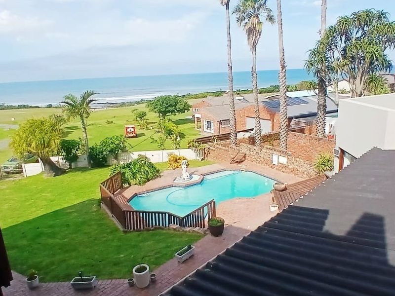 Elevated view overlooking a private swimming pool, landscaped garden, and coastal scenery with ocean views.