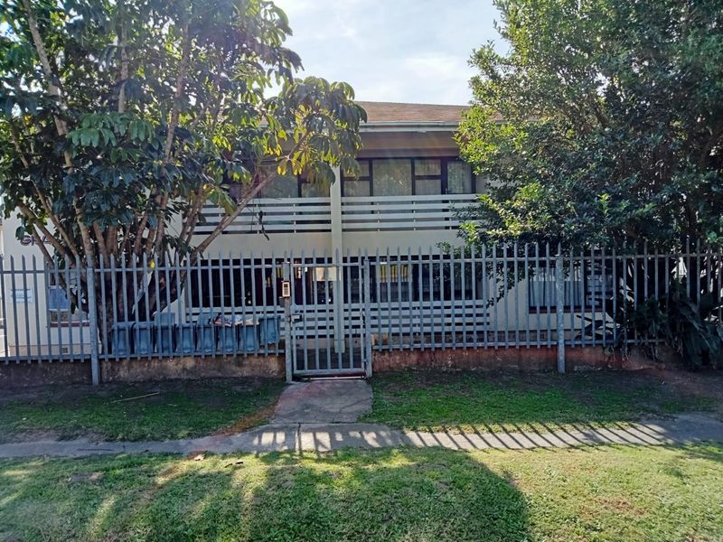 Front elevation of the apartment building featuring steel palisade fencing, a secure pedestrian gate, and a balcony with horizontal railings.