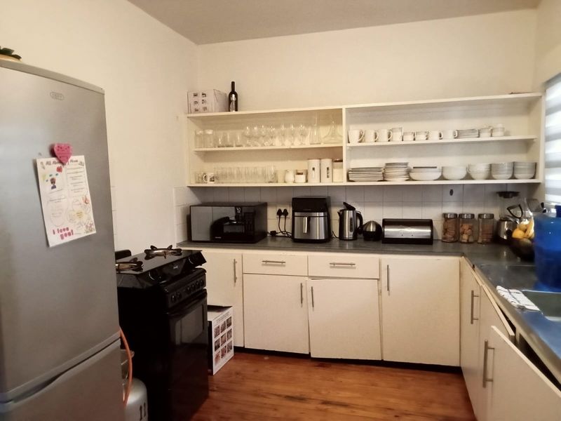 A functional kitchen featuring white cabinetry, open shelving, laminate countertops, a gas stove, and a tiled backsplash.