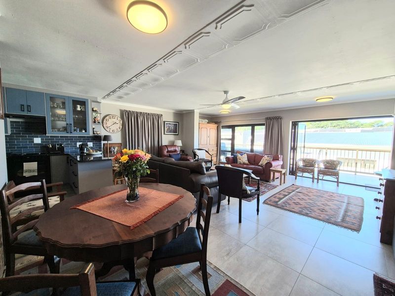 Spacious open-plan living area featuring tiled floors, decorative ceiling details, a modern kitchen with subway tile backsplash, and direct access to a balcony.