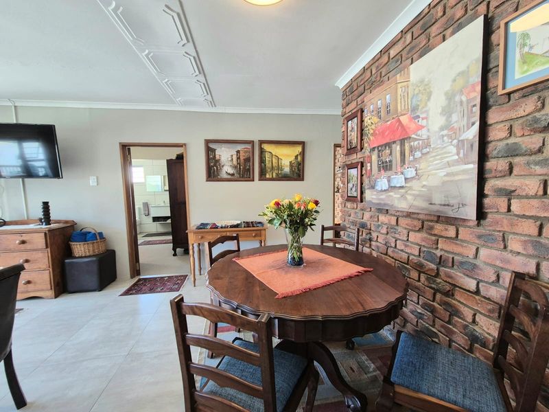 Dining area featuring an exposed brick feature wall, decorative ceiling molding, and neutral tiled flooring, providing a warm and textured living space.