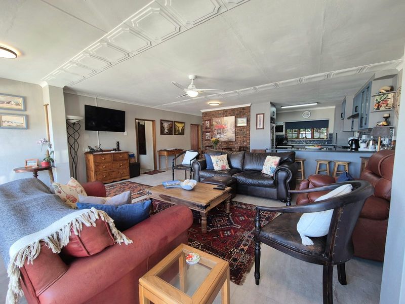 Spacious open-plan living area featuring a kitchen with island, exposed brick accent wall, and decorative ceiling details, creating a comfortable and functional living space.