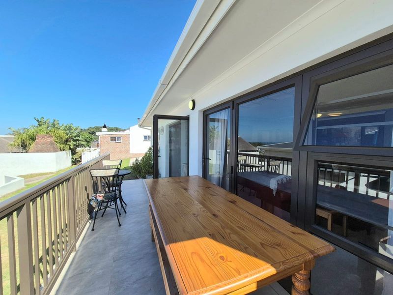 A spacious outdoor balcony featuring tiled flooring, a secure metal balustrade, and large aluminium sliding doors providing seamless access to the interior living space.