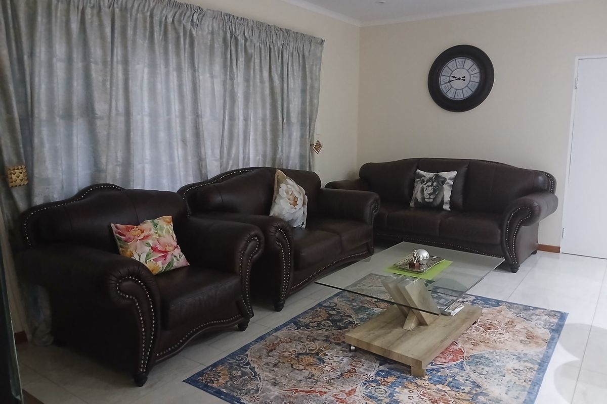 A living room featuring neutral walls, tiled flooring, and recessed ceiling lighting, providing a functional and well-maintained space.