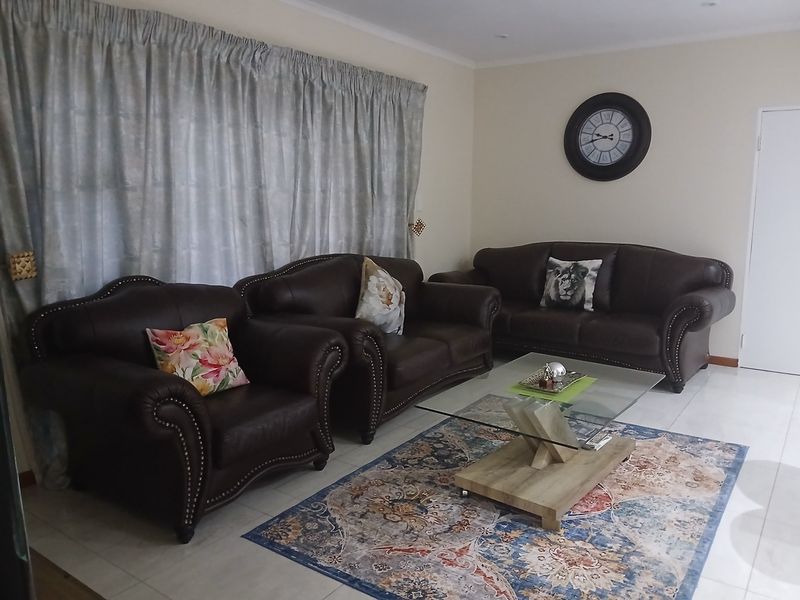 A living room featuring neutral walls, tiled flooring, and recessed ceiling lighting, providing a functional and well-maintained space.