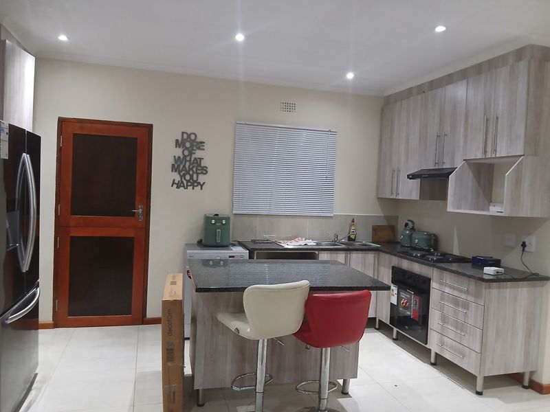 Modern kitchen featuring light wood-grain cabinetry, granite countertops, built-in oven, gas hob, and recessed lighting, offering a functional and contemporary workspace.