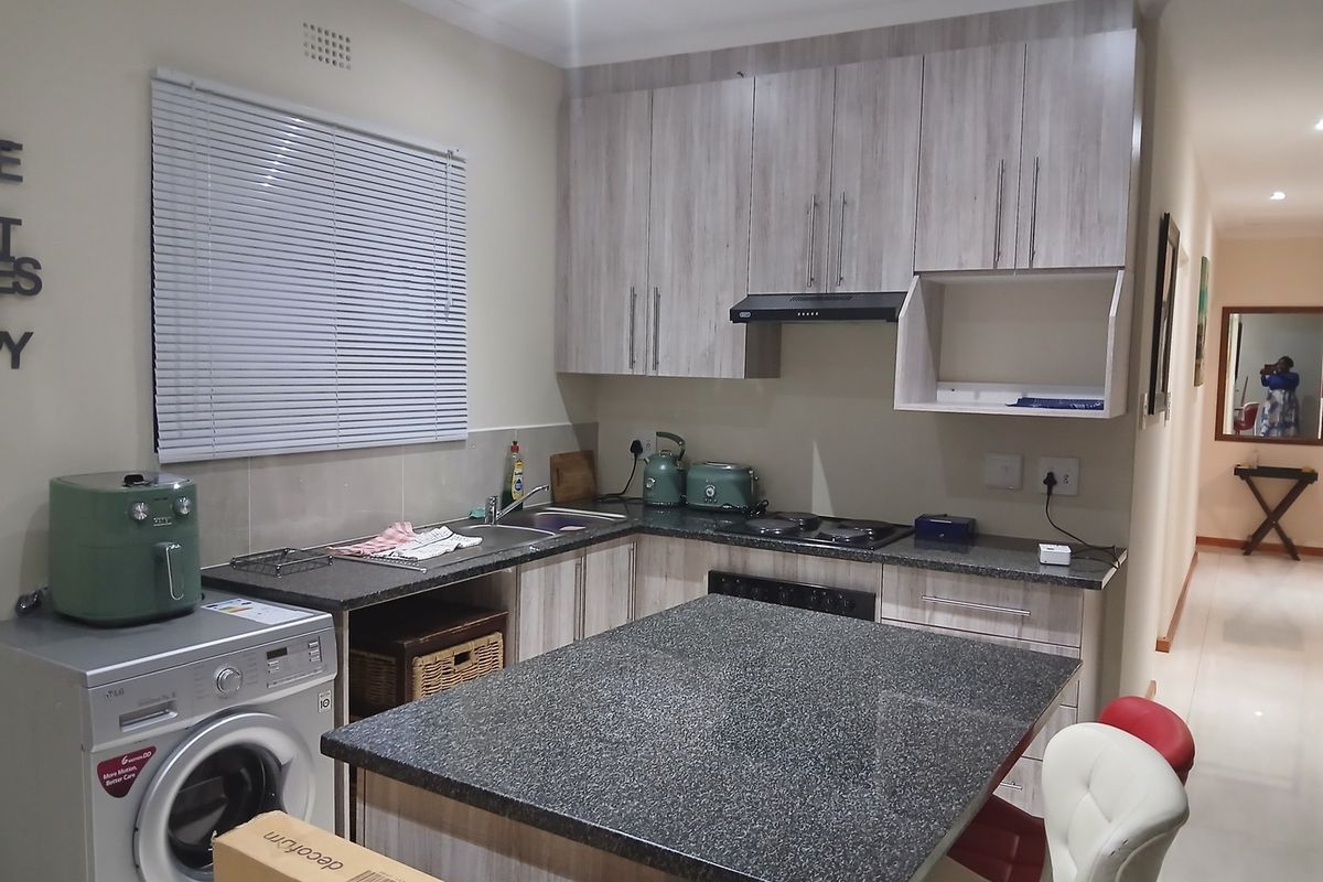 Modern kitchen featuring light wood-grain cabinetry, granite countertops, a central island, and integrated appliances, offering a functional and contemporary cooking space.
