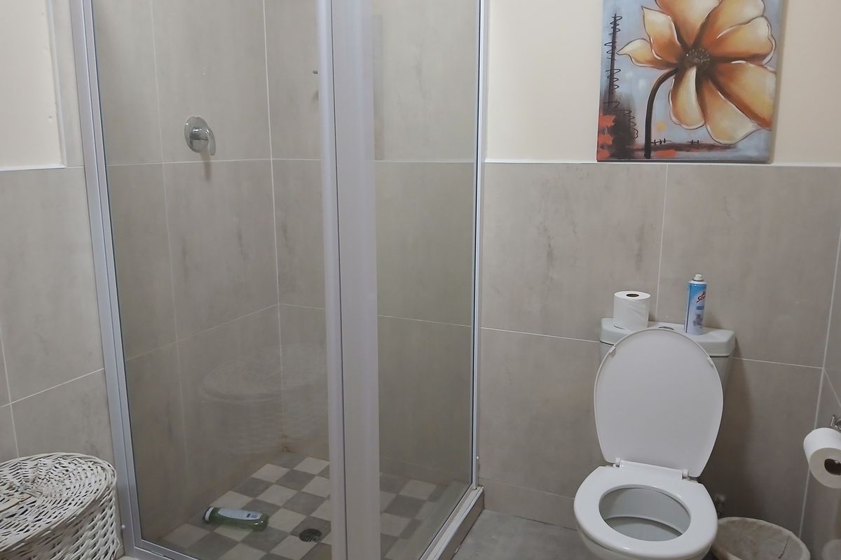 A functional bathroom featuring a glass-enclosed shower, tiled walls, and a standard toilet, providing a clean and practical space.