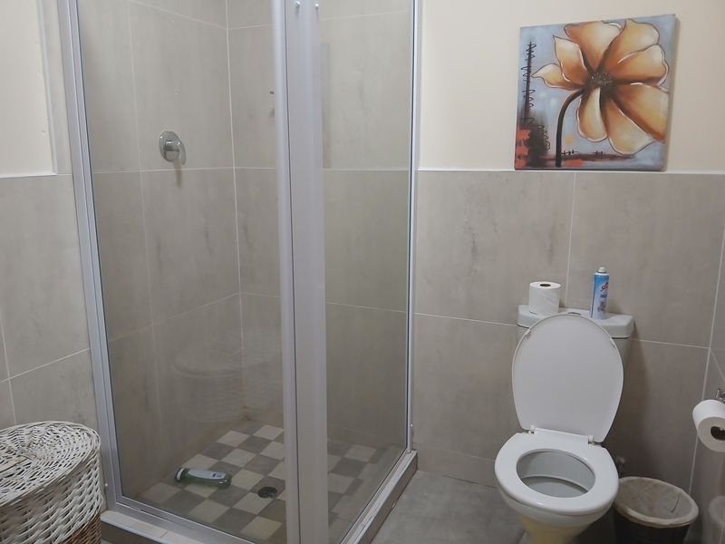 A functional bathroom featuring a glass-enclosed shower, tiled walls, and a standard toilet, providing a clean and practical space.
