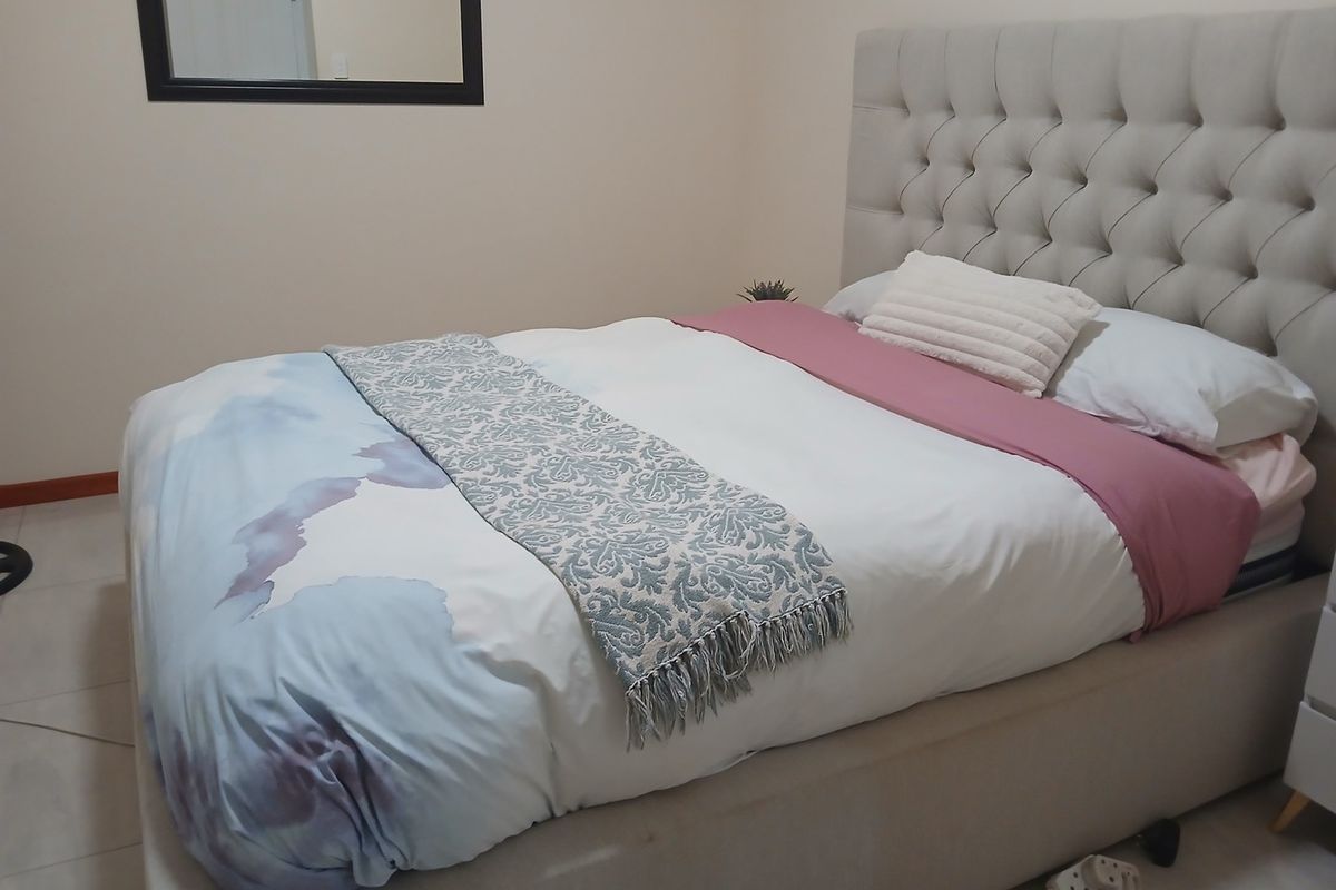 A well-maintained bedroom featuring neutral wall tones and tiled flooring, providing a clean and functional living space.