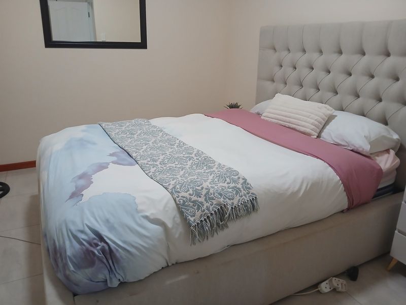 A well-maintained bedroom featuring neutral wall tones and tiled flooring, providing a clean and functional living space.