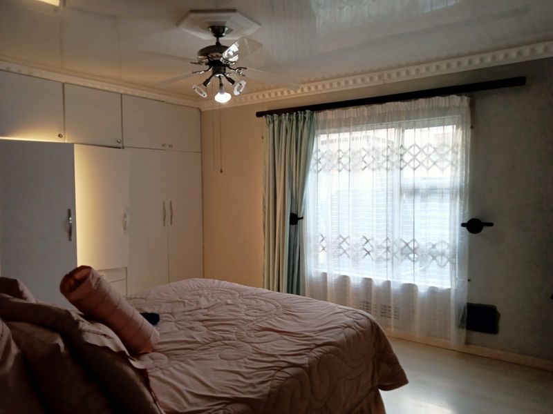 A bedroom featuring built-in cupboards, a ceiling fan, and decorative ceiling cornices, providing functional storage and classic architectural detailing.